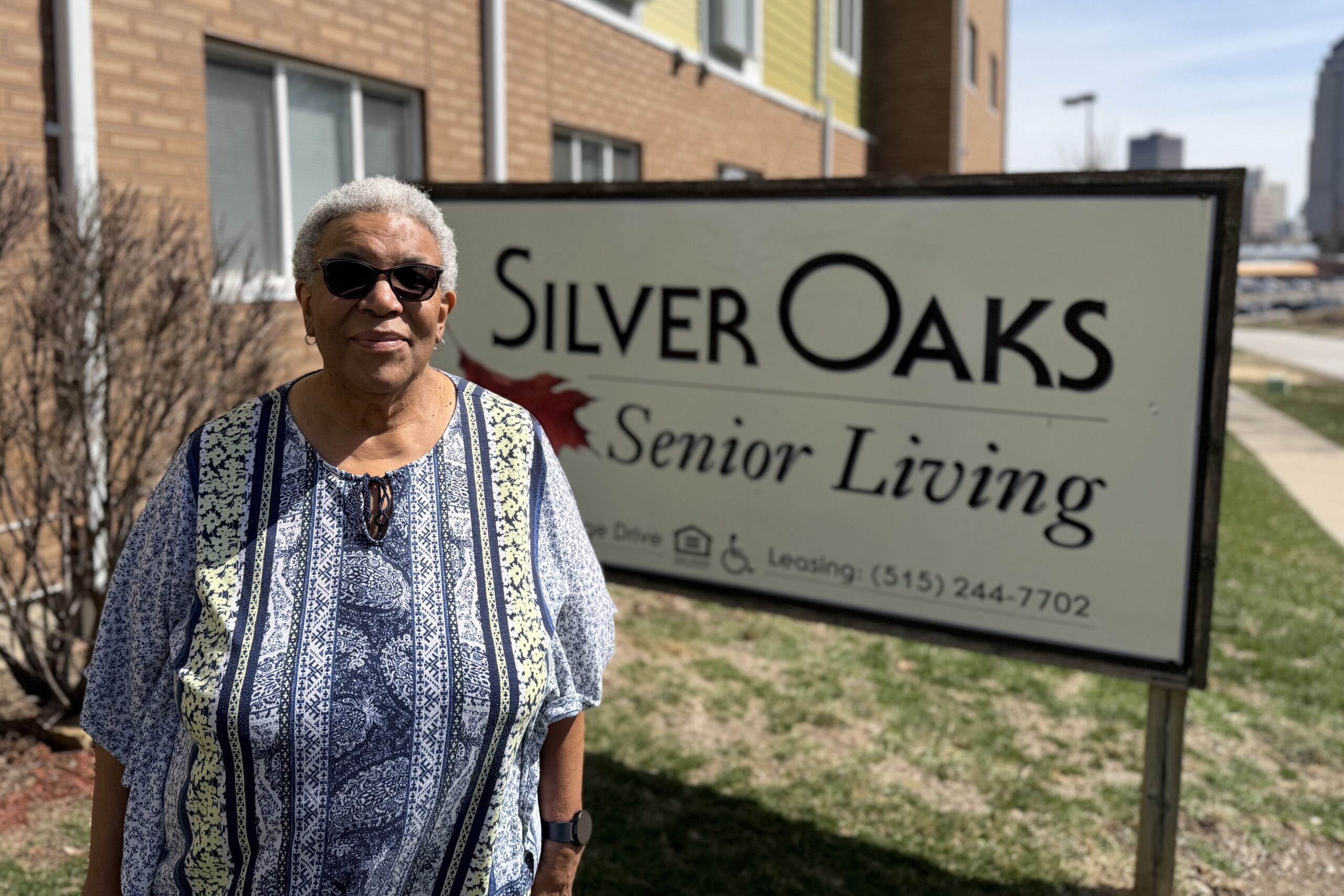 Matthea Little Smith stands in front of a sign for Silver Oaks Senior Living